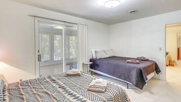 A bedroom with a bed, a bedside table, a window, and a door.