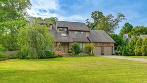 Une maison à deux étages avec une grande pelouse devant, un garage et une véranda couverte.