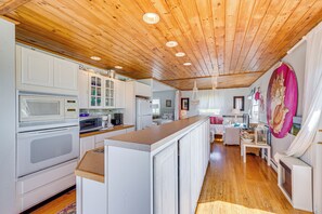 Cocina con armarios blancos, techo de madera y una isla central.