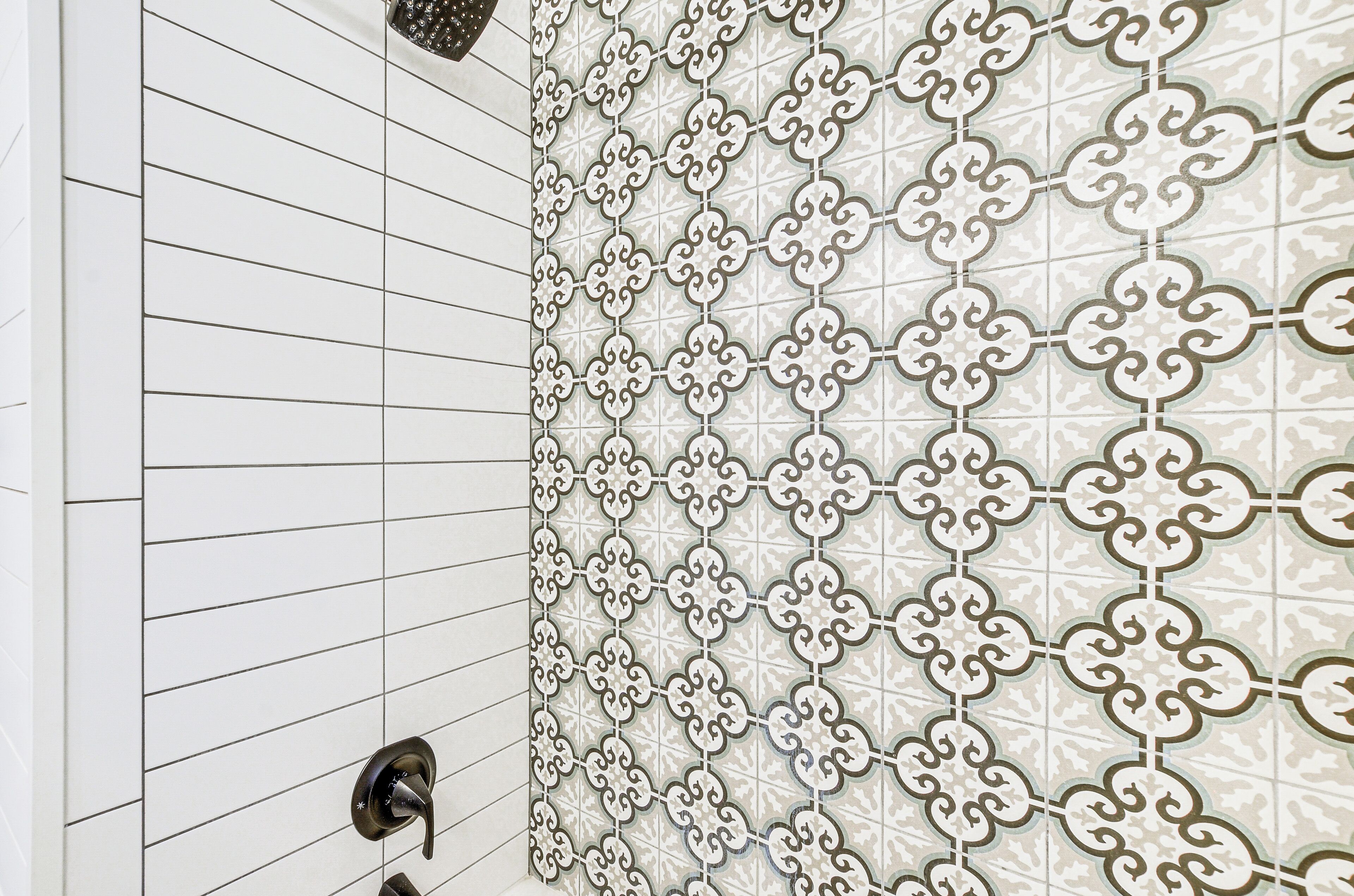 A bathroom with white tiled walls and a decorative tile pattern on the right side.