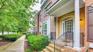 A residential house with a front porch, brick facade, and a well-maintained lawn. - 3 Mi to Avalon: Townhome w/ Balcony in Alpharetta! (Milton)