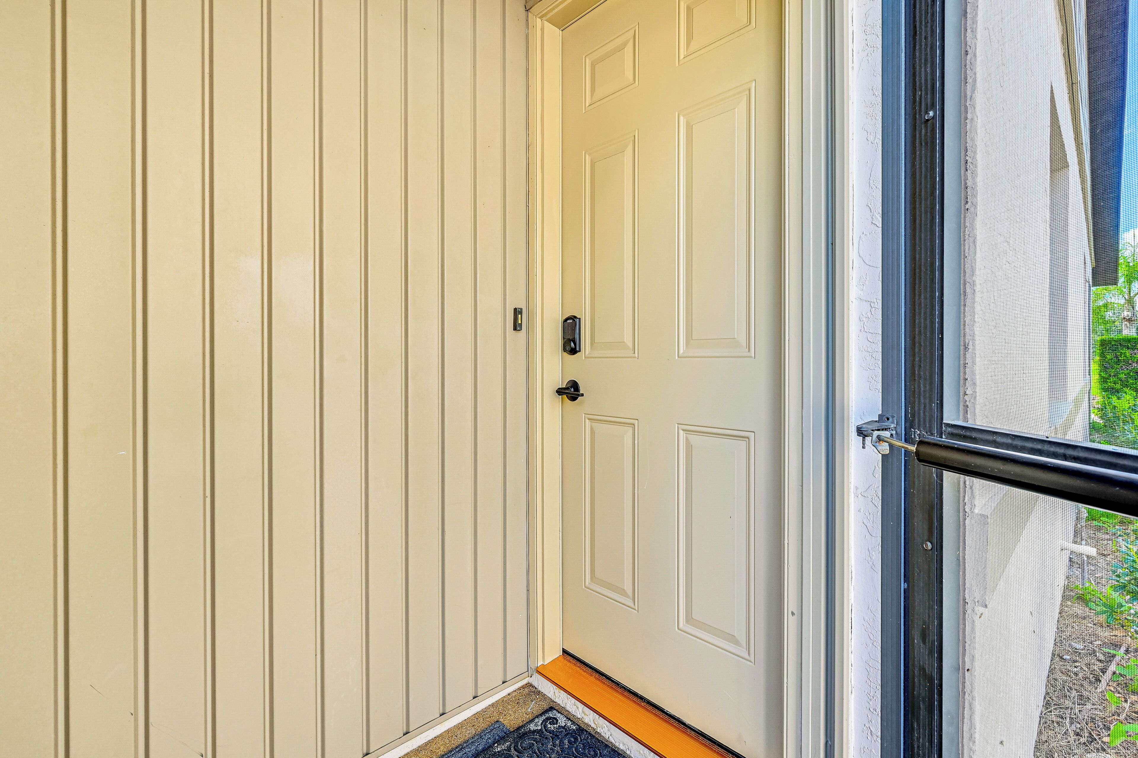 A white door with a black handle and a doormat at the entrance.
