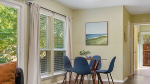 Zona pranzo con tavolo e sedie, una finestra con persiane e un quadro appeso al muro.
