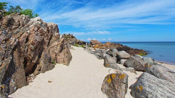 Un sendero pedregoso que conduce al mar bajo cielos despejados.