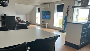 A modern kitchen with a dining area, a TV, and a view of the outdoors. - 4 Person Holiday Home in Ribe (Ribe)