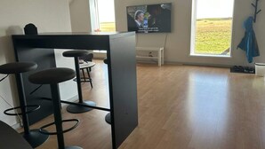 A modern bar area with stools, a television, and large windows with a view of the outdoors. - 4 Person Holiday Home in Ribe (Ribe)