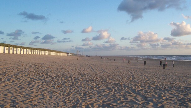 A wide sandy beach with a row of white buildings along the shore. - Lovely Holiday Home in Texel Near Sea (Oosterend)