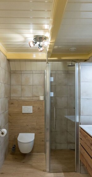 Ein Badezimmer mit Dusche, Toilette und einer Holzwand.