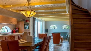 A modern kitchen with wooden cabinets, a dining area with red chairs, and a staircase leading to another level. - Lovely Holiday Home in Texel Near Sea (Oosterend)