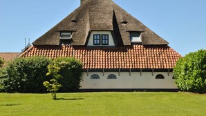 A traditional house with a steeply pitched thatched roof, a tiled roof, and a small window. - Lovely Holiday Home in Texel Near Sea (Oosterend)