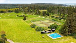 An aerial view of a large, green field with a tennis court, a swimming pool, and a small boat. - 6 Person Holiday Home on a Holiday Park in Hanstholm (Hanstholm)