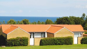 Una serie di edifici in mattoni con tetti in tegole arancioni, infissi bianchi e vista sul mare.