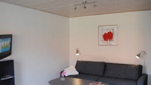 Un soggiorno moderno con un divano grigio, un tavolino, una TV su un mobile basso e un'opera d'arte incorniciata al muro.