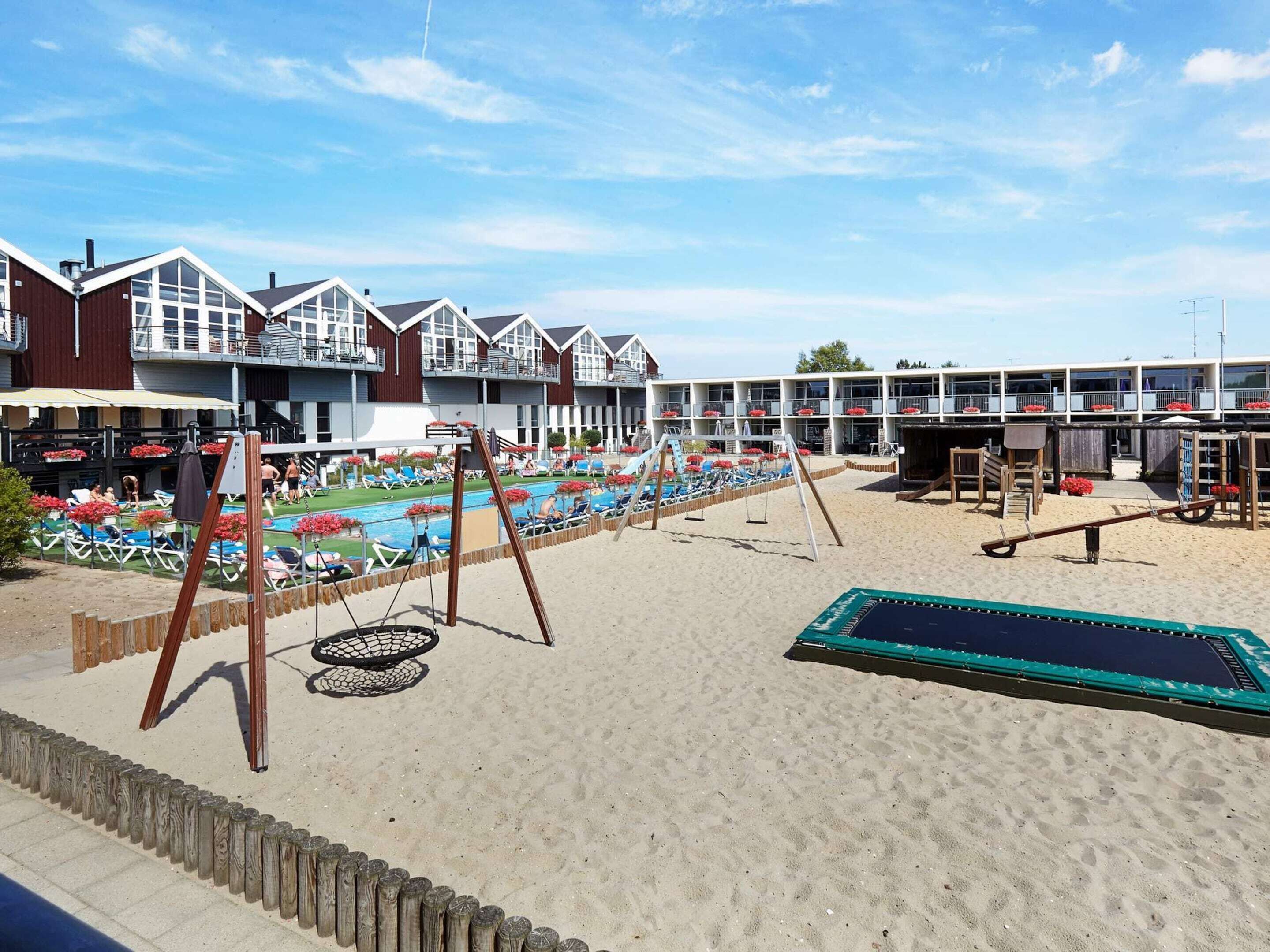 A beachside hotel with multiple balconies, a swimming pool, and beach chairs.