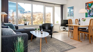 A modern living room with a sofa, coffee table, and dining area. - 6 Person Holiday Home on a Holiday Park in Ringkobing (Ringkobing)