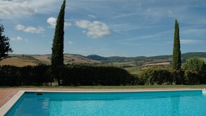 Une piscine offrant une vue sur des collines verdoyantes et de grands arbres.