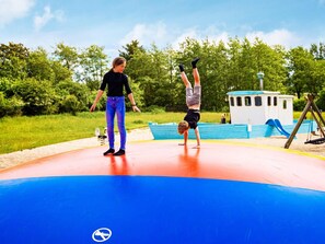 Children can play safely on the rubberized playground surface surrounded by lush greenery.