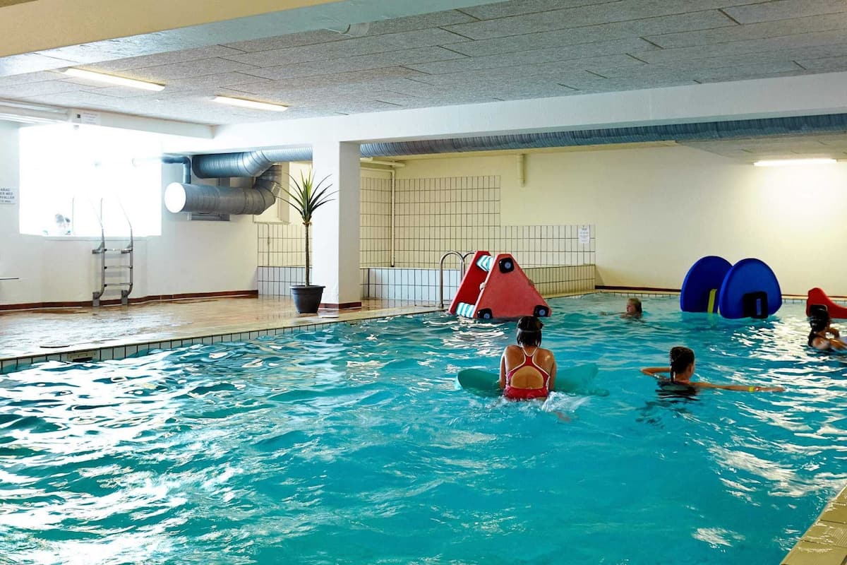 En inomhuspool med en stege, en krukväxt och uppblåsbara leksaker.