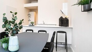 Une cuisine moderne avec des meubles blancs, un plan de travail noir et une plante suspendue.