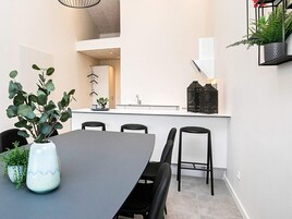 A modern kitchen with white cabinets, a black countertop, and a hanging plant.