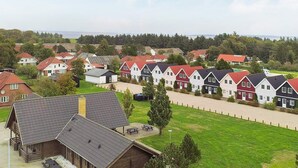 Ein Wohngebiet mit Häusern mit roten und weißen Fassaden, einer Holzhütte und einem grünen Feld.