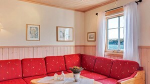 Una habitación acogedora con un sofá rojo, una mesa de madera y una ventana con vistas al mar.