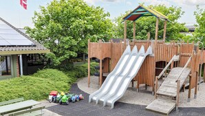A playground with a slide, climbing structures, and a picnic table with toy vehicles.