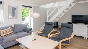 A modern living room with a sofa, two chairs, a table, a TV, and a staircase. - 4 Person Holiday Home in Romo (Rømø)