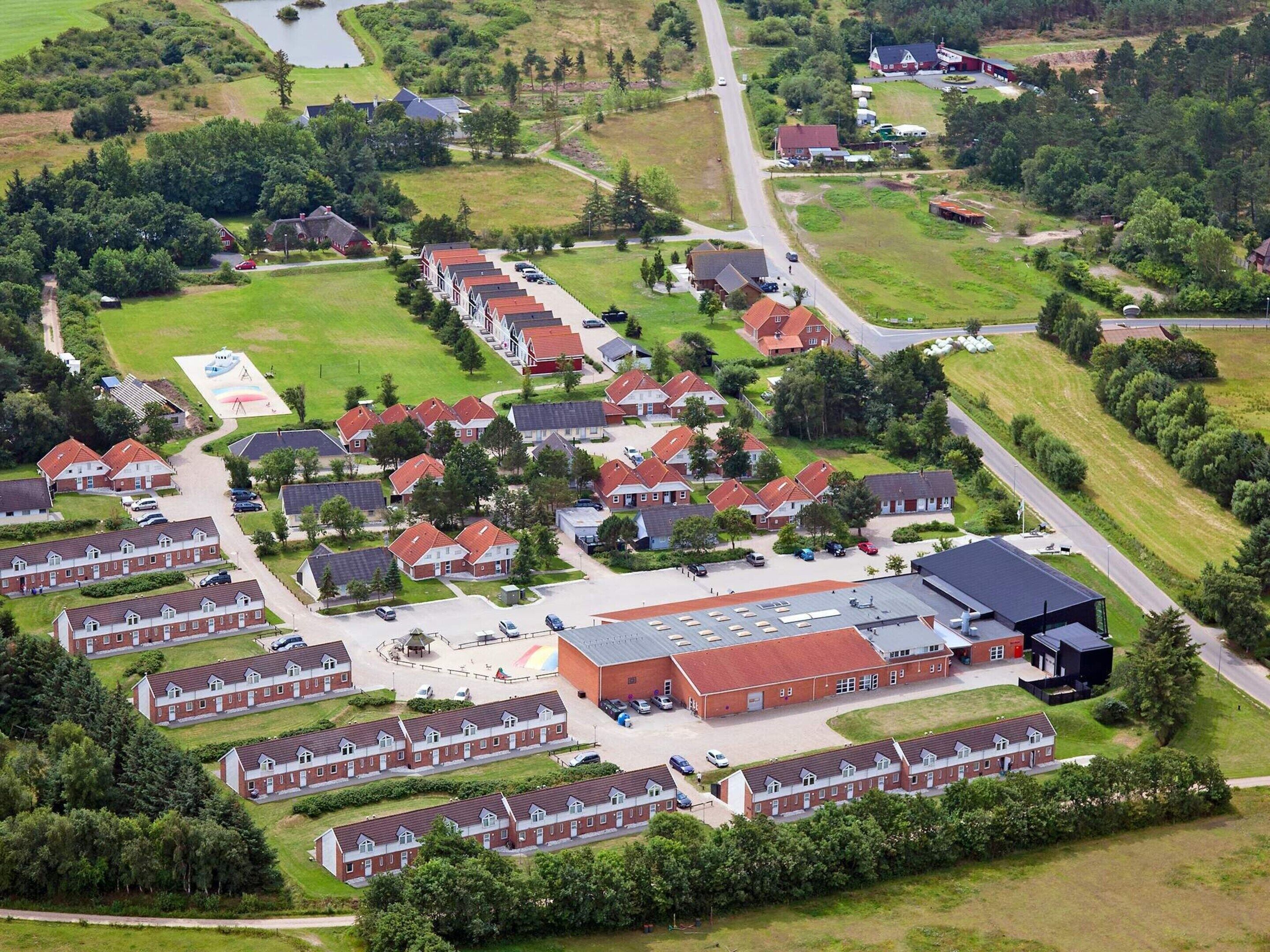 Un quartier résidentiel comprenant plusieurs maisons, un bâtiment central doté d’un toit plat et une route.