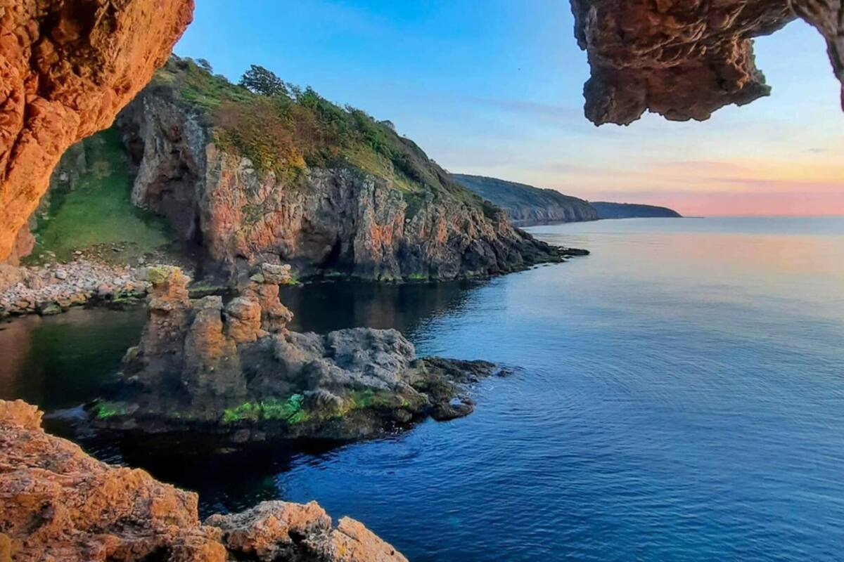 A coastal landscape with rocky cliffs and calm sea.