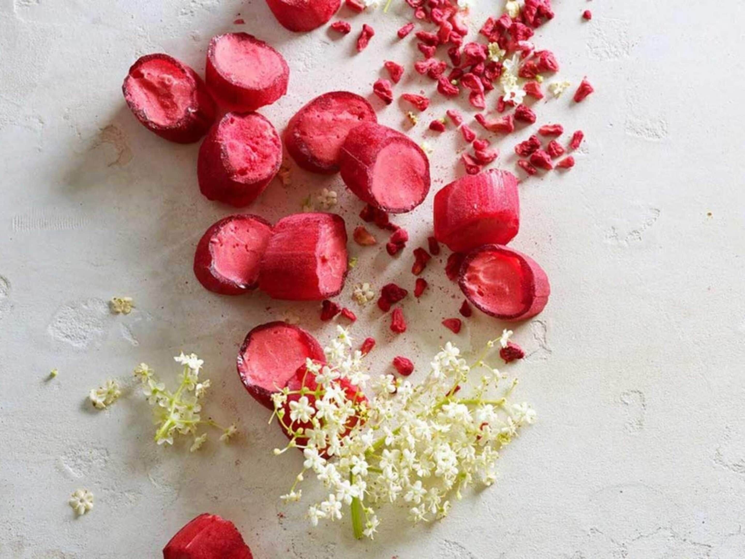 Des betteraves rouges coupées en tranches et des fleurs blanches sur une surface texturée.
