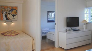 Een slaapkamer met een bed, een dressoir, een televisie en een schilderij aan de muur.