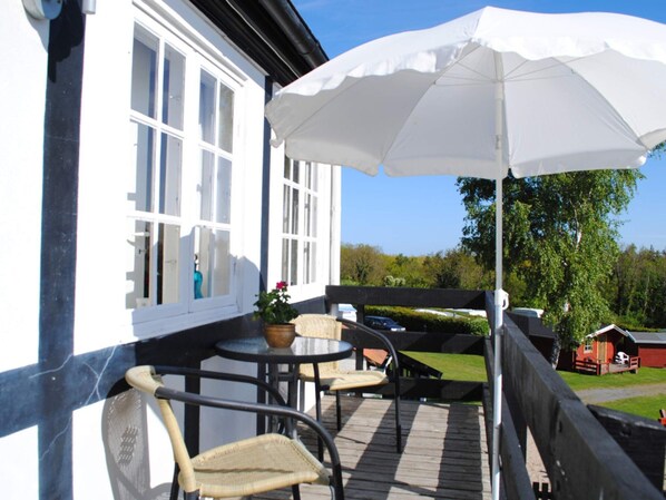 Relax on the patio with a round table and two comfortable chairs, surrounded by lush greenery and a scenic view.