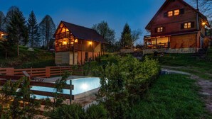 Eine Holzhütte mit Schwimmbecken, umgeben von Grünpflanzen und Bäumen.