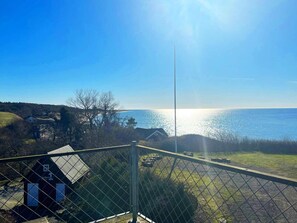 A coastal view from a balcony with a metal fence, a small building labeled '1', and a clear sky. - 2 Person Holiday Home in Aakirkeby (Akirkeby)