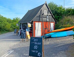 A small wooden building with a sign for 'boder' and paddle boarding equipment. - 2 Person Holiday Home in Aakirkeby (Akirkeby)