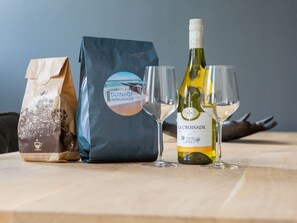 Ein Tisch mit einer Kaffeepackung, einer Weinflasche und zwei Weingläsern.
