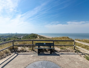A bench overlooking a beach with a clear view of the ocean and distant city skyline.