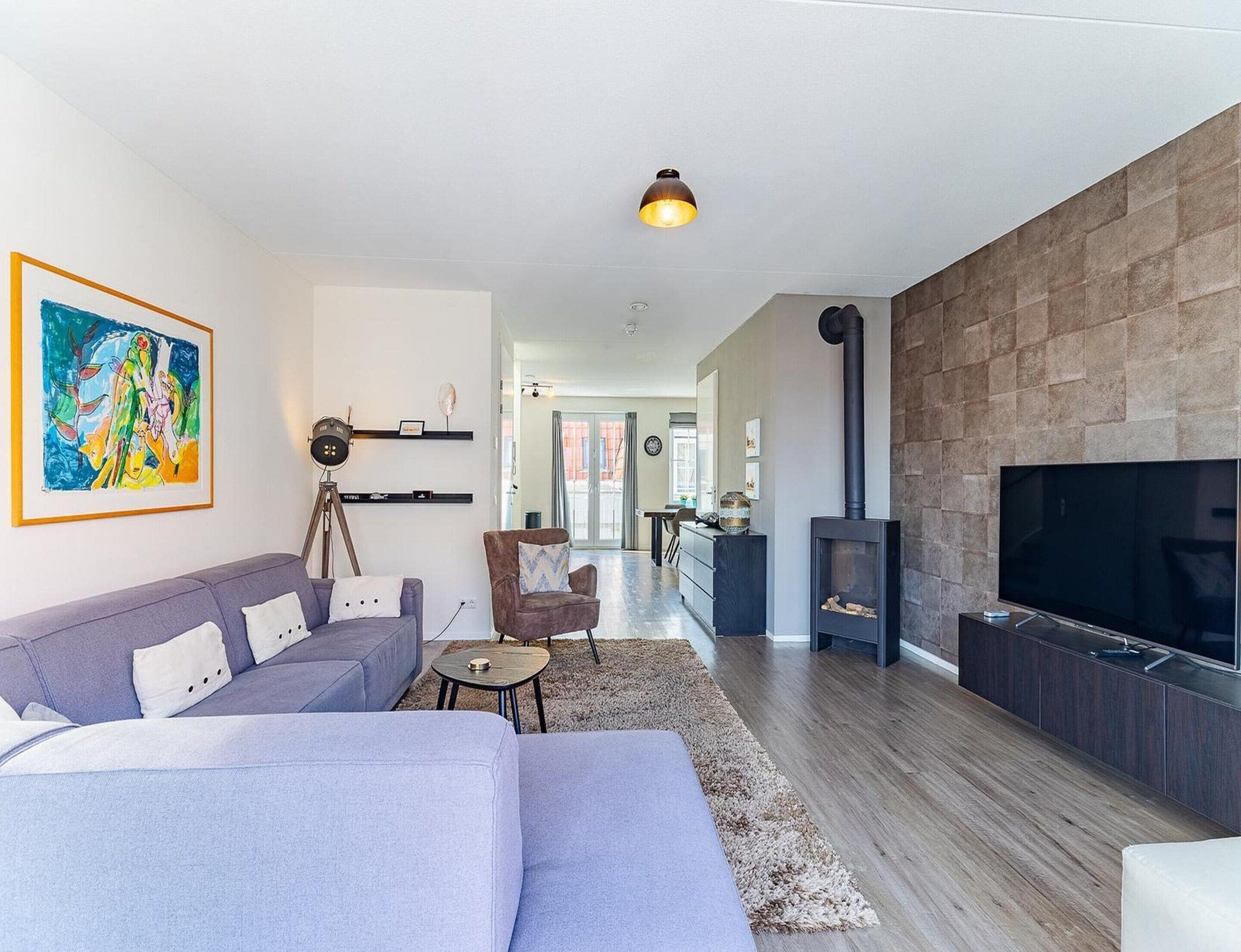 A modern living room with a sofa, a television, a fireplace, and a painting on the wall.