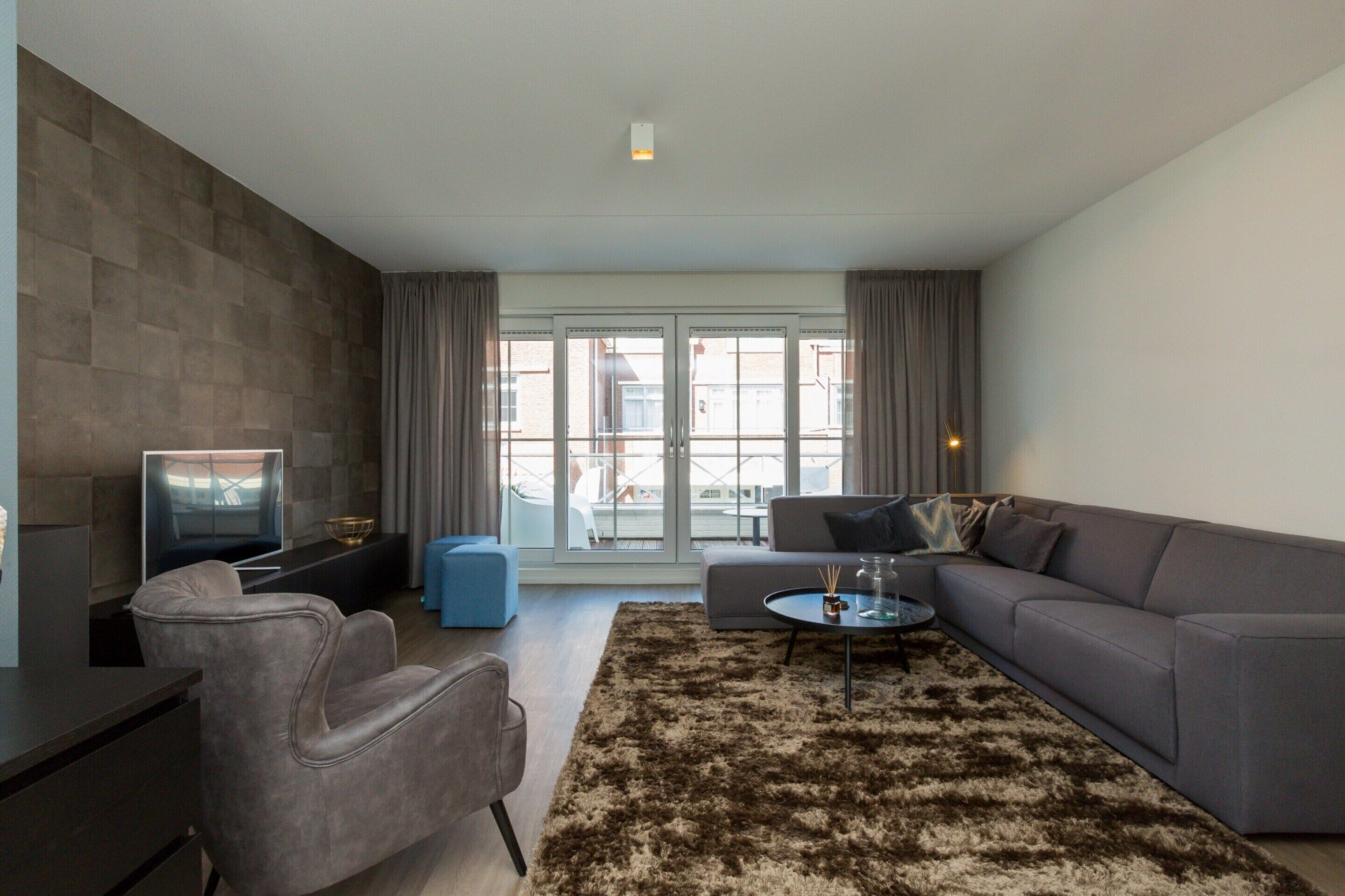 A modern living room with a sofa, armchairs, a coffee table, and a TV.