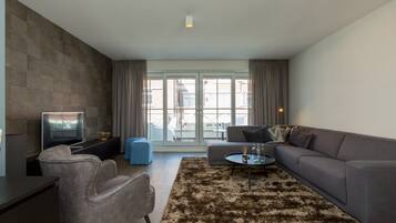 A modern living room with a sofa, armchairs, a coffee table, and a TV.