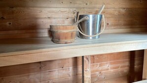 Uno scaffale di legno con un secchio di metallo e una pentola di metallo con manico.