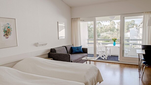 Une chambre d’hôtel avec deux lits, un canapé, une table et un balcon avec vue.