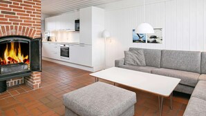 Ein modernes Wohnzimmer mit Kamin aus Ziegelsteinen, weißen Schränken, einem grauen Sofa und einem weißen Couchtisch.