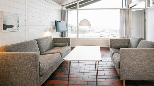 Ein modernes Wohnzimmer mit einem weißen Sofa, einem weißen Couchtisch und einem Fernseher an der Wand.