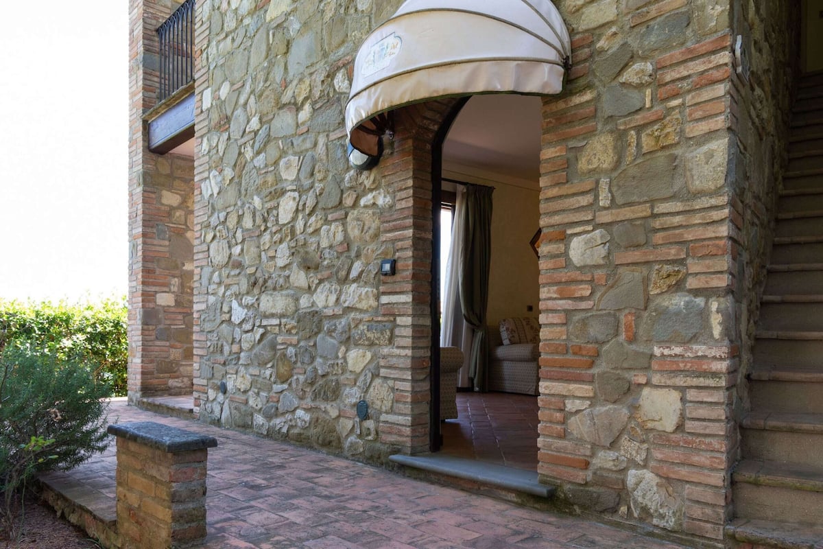 A stone building with a covered entrance and a small outdoor area with steps leading up to it.