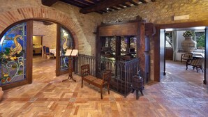 A rustic interior with a wooden bench, a piano, and a stained glass window. - Elegant Apartments in Resort With Swimming Pool set in Nature (Collazzone)