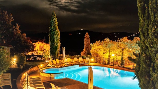 A nighttime pool area with a crescent moon in the sky, surrounded by trees and a distant mountain range. - Elegant Apartments in Resort With Swimming Pool set in Nature (Collazzone)