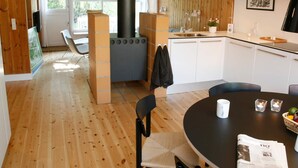 A modern kitchen with a central stove, white cabinets, and a dining area with a round table and chairs. - 6 Person Holiday Home on a Holiday Park in Vaeggerlose (Vaeggerlose)