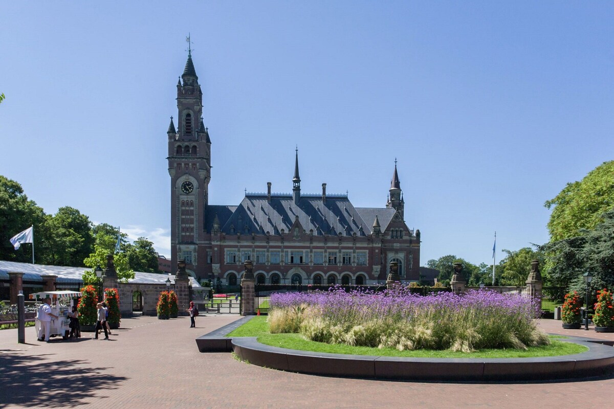 Un bâtiment historique doté d’une tour horlogée, d  ’une cour centrale agrémentée de fleurs et d’un chemin piétonnier dallé.